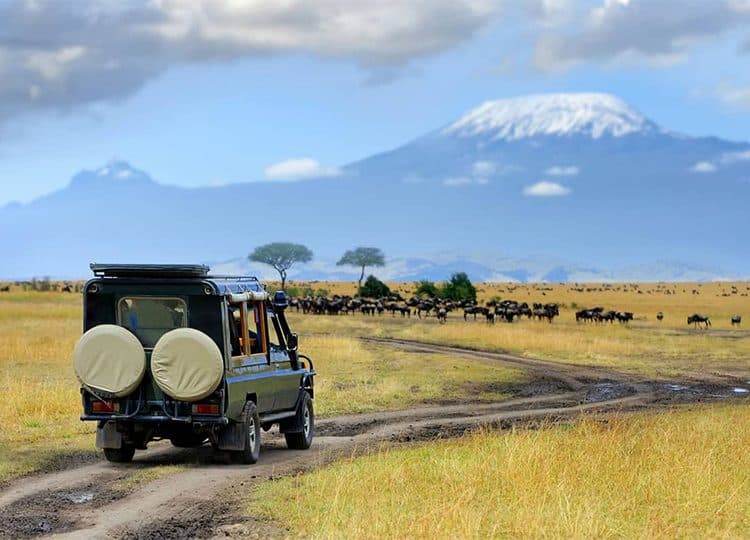A safari vehicle crossing the Amboseli plains beneath Mount Kilimanjaro